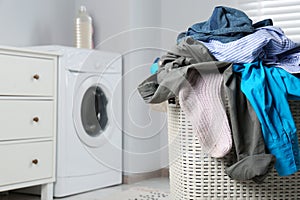 Plastic laundry basket overfilled with clothes in bathroom, closeup. Space for text