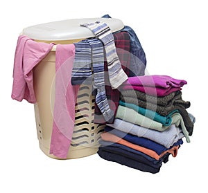 Plastic laundry basket, from under the cover of which you can see different clothes and a stack of clothes next to the floor