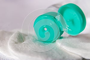 Plastic liquid bottle with green cap close-up, small cosmetic bottle on cotton pads, personal care product concept