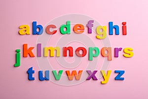 Plastic magnetic letters on pink background. Alphabetical order