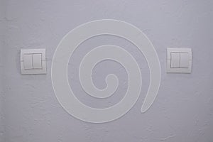 Plastic mechanical white light switch, installed on a light gray wall