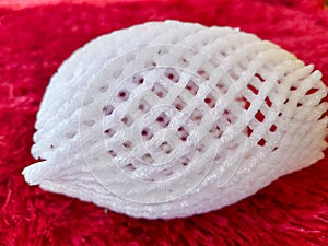 Close up of fruit protection foam net on red background.