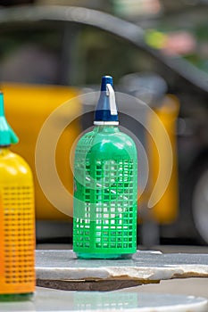 Plastic mesh siphon in orange yellow and other old and vintage green for soda on top of small round high tables on the terrace