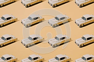 Plastic and metal old toy. Beige limousine. Oldtimer on yellow gold luxury background. Pattern