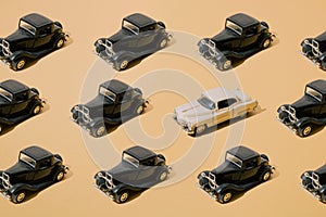 Plastic and metal old toy. Black retro car with beige limousine. Oldtimer on yellow gold luxury background. Pattern