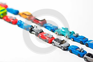 Plastic multi-colored toy cars are lined up on a white background. Stereotypical alignment of subjects is a sign of autism. photo