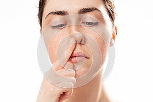 Plastic nose surgery. Close up face of young caucasian woman touching her crooked nose isolated on white background