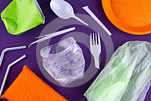 Plastic orange green waste collection on purple background. Concept of plastic pollution and ecology problem