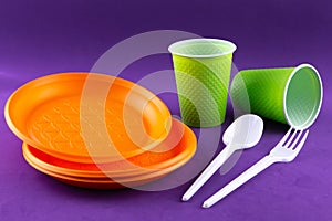 Plastic orange green waste collection on purple background. Concept of plastic pollution and ecology problem