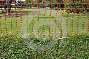 Plastic orange net or fence and green grass