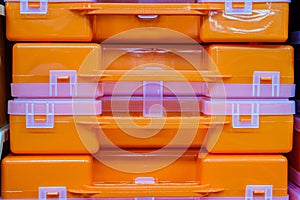 Plastic orange tool boxes on store shelves. Stack of organizers close-up