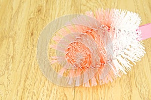 Plastic orange and white toilet brush on wood background