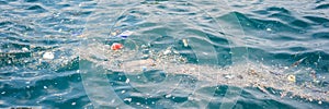 Plastic and other debris floats in blue water. Plastic garbage polluting seas and ocean BANNER, LONG FORMAT