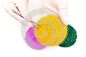 Plastic pellets . Colorant for polymers . granules. Plastic pellets in the hands with gloves and tweezers