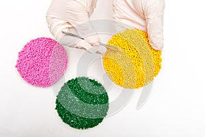 Plastic pellets . Colorant for polymers in granules. Worker wearing gloves takes plastic pellets with tweezers