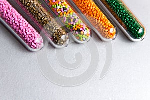 Plastic pellets .Polymeric dye in test tubes on gray background.