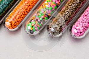 Plastic pellets .Polymeric dye in test tubes on gray background