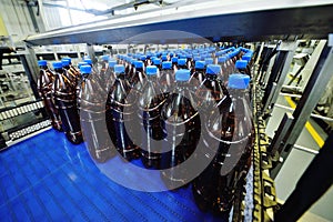 Plastic PET bottles with drinks or beer are moving on a conveyor belt in the background of the factory.