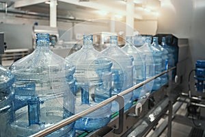 Plastic PET bottles or gallons on production line or conveyor belt in water factory for bottling pure drinking water