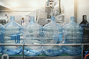 Plastic PET bottles or gallons on production line or conveyor belt in water factory for bottling pure drinking water