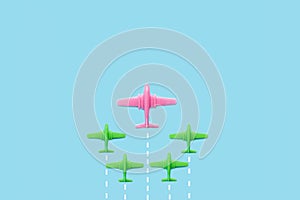 Plastic pink and green toy aeroplanes on a light blue background