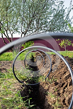 plastic pipe for supplying water to a drip irrigation system, twisted into a spiral, lies on top of a dug ditch