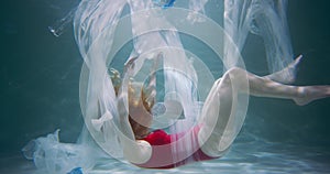 Plastic pollution concept. Cinematic shot, young woman sinks under water, garbage waste floating around slow motion.