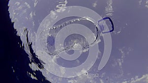 Plastic pollution of the Ocean. Big plastic bottle barrel with handle swims on surface of the blue water, on background of the b