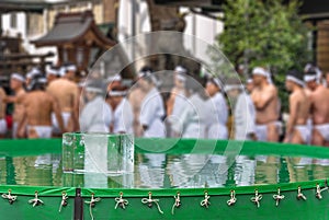 A plastic pool filled with cold water containing a huge block of ice at Tokyo's Teppozu Shrine.