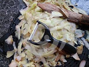 Plastic potato peeler with fresh white potato peelings