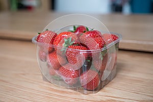 Plastic punnet of strawberries on a wooden table