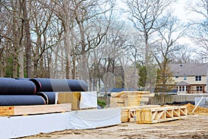 Plastic PVC pipes stacked at wooden building materials stack of boards wood frame on beam construction