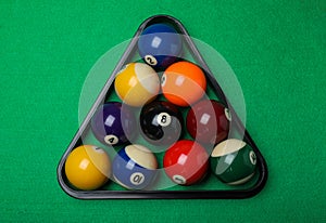 Plastic rack with billiard balls on green table, top view