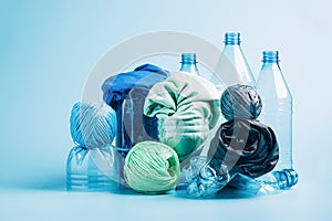 Empty plastic bottle and various fabrics made of recycled polyester fiber synthetic fabric on a blue background