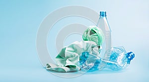 Empty plastic bottle and various fabrics made of recycled polyester fiber synthetic fabric on a blue background photo