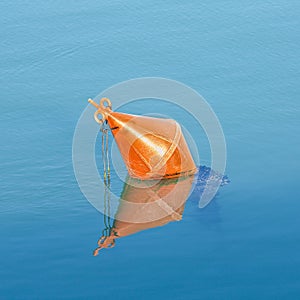 Plastic red bouy on a calm lake isolated on blue background