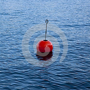 Plastic red bouy on a calm lake isolated on blue background