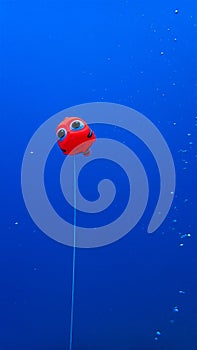 Plastic red clown fish floating in the deep blue sea