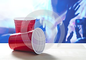 2 plastic red party cups on a table. One on its side.