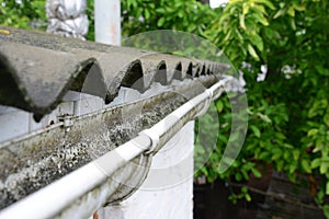 Plastic roof guttering, rain guttering & drainage with old asbestos roof.