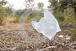 Plastic rubbish bags hanging on the barbed wire in the forest