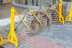 Plastic safety barrier protects road work area. Yellow-black plastic fence near street repair site. Outdoor construction work,