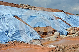 The plastic sheet is spread over the surface of the slope to prevent erosion.