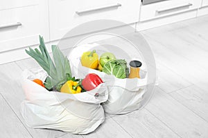 Plastic shopping bags full of  and juice on floor in kitchen. Space for text