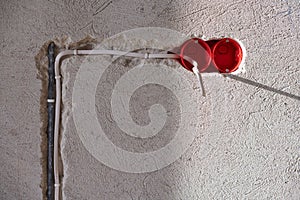 Plastic socket box and electrical wires on plastered wall