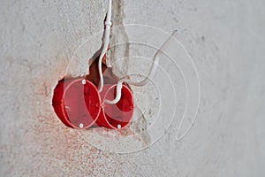 Plastic socket box and electrical wires on plastered wall