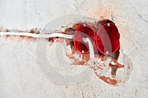 Plastic socket box and electrical wires on plastered wall