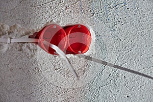 Plastic socket box and electrical wires on plastered wall