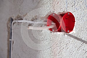 Plastic socket box and electrical wires on plastered wall