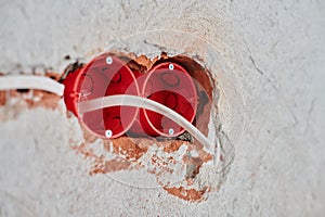 Plastic socket box and electrical wires on plastered wall